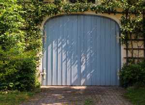 beautiful blue garage door surrounded by wild flowers